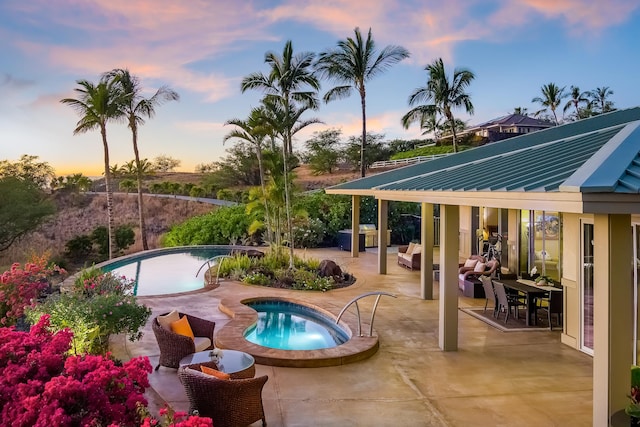 pool at dusk featuring a gazebo, a jacuzzi, and a patio area