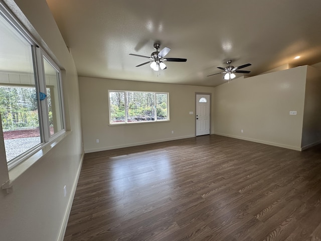 empty room with ceiling fan, a healthy amount of sunlight, and dark wood-type flooring