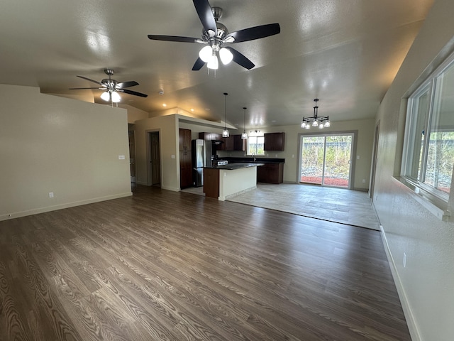 unfurnished living room featuring dark hardwood / wood-style floors and ceiling fan with notable chandelier