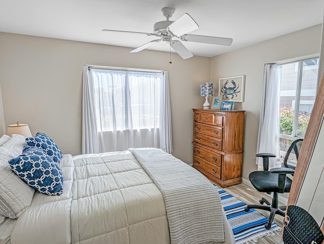 bedroom featuring ceiling fan, hardwood / wood-style flooring, and multiple windows