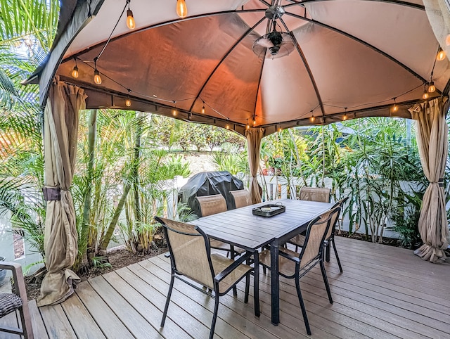 wooden terrace with grilling area, ceiling fan, and a gazebo