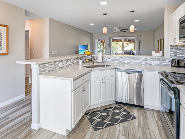 kitchen featuring ceiling fan, kitchen peninsula, white cabinetry, hanging light fixtures, and appliances with stainless steel finishes