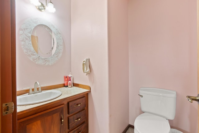 bathroom featuring toilet, vanity, and an inviting chandelier