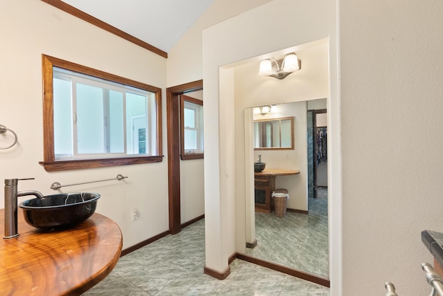 bathroom featuring vaulted ceiling, ornamental molding, and sink