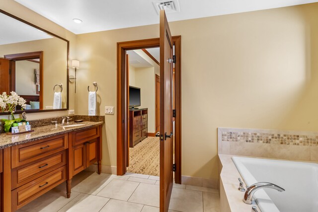 bathroom featuring visible vents, baseboards, vanity, a bath, and tile patterned floors