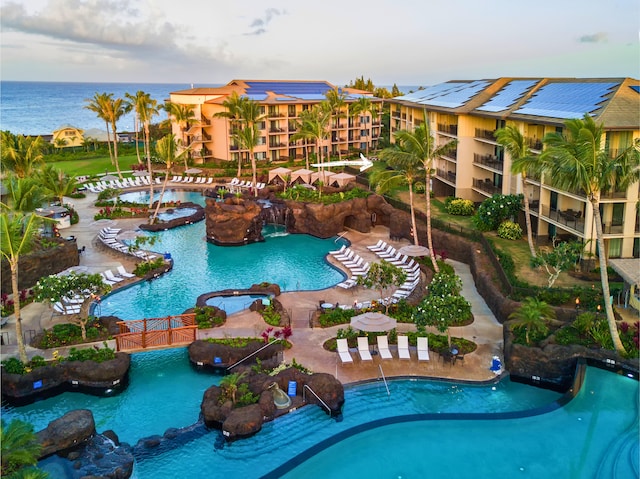 community pool featuring a water view, a jacuzzi, and a patio