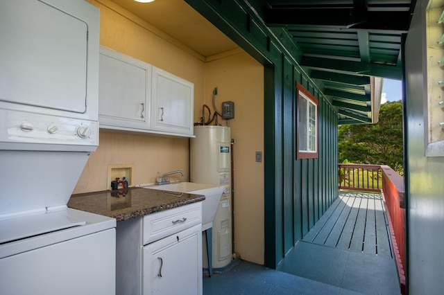 kitchen with stacked washer / dryer, dark stone countertops, white cabinets, and water heater