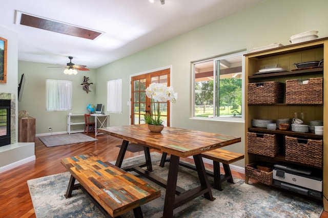 dining area featuring dark wood-type flooring, ceiling fan, and a fireplace