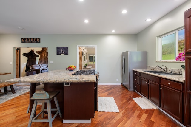 kitchen featuring sink, hardwood / wood-style flooring, a breakfast bar area, stainless steel fridge, and a center island