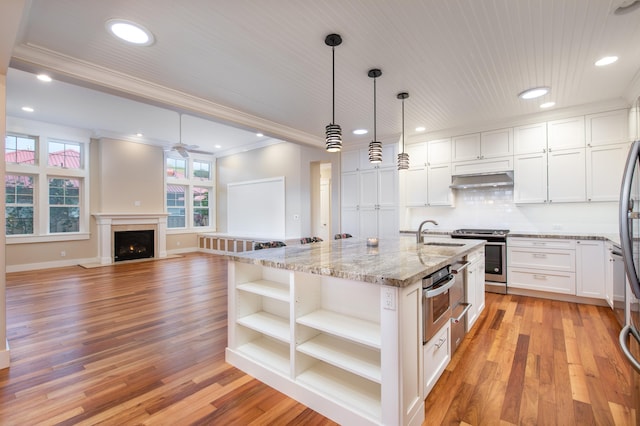 kitchen featuring light hardwood / wood-style floors, a kitchen island with sink, hanging light fixtures, stainless steel stove, and white cabinets