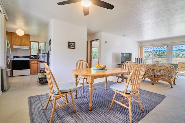 dining area featuring light carpet and a textured ceiling