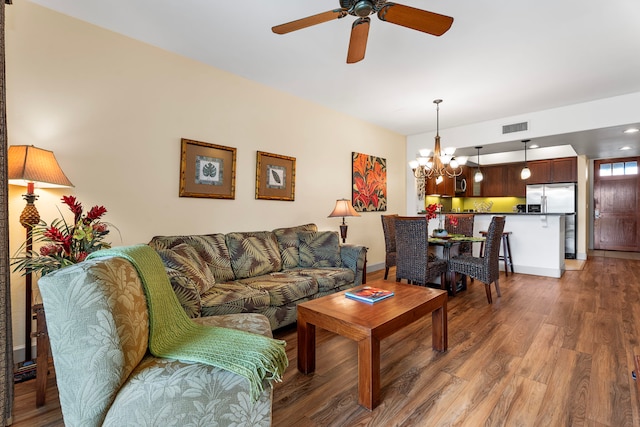 living room with dark wood-type flooring and ceiling fan with notable chandelier