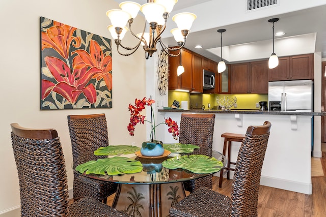 dining area with hardwood / wood-style flooring and a notable chandelier