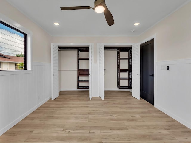 unfurnished bedroom featuring two closets, ceiling fan, and light wood-type flooring