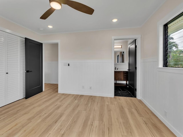 unfurnished bedroom with ensuite bathroom, light wood-type flooring, and ceiling fan