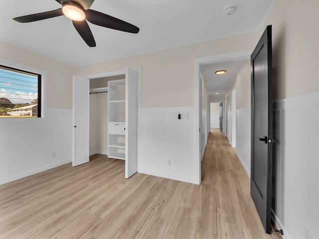 unfurnished bedroom with ceiling fan, light wood-type flooring, and a closet