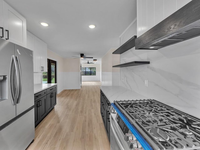 kitchen with white cabinetry, stainless steel appliances, custom range hood, light stone counters, and light hardwood / wood-style flooring