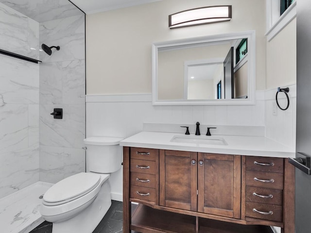 bathroom featuring toilet, tiled shower, and vanity