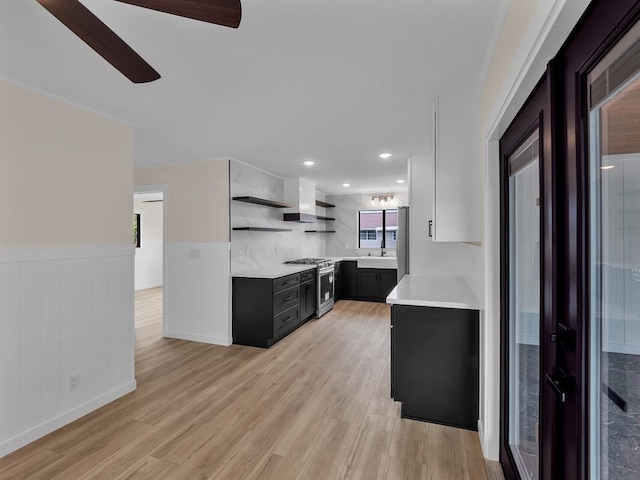 kitchen with light hardwood / wood-style floors, stainless steel range, ceiling fan, white cabinetry, and tasteful backsplash