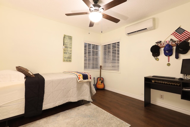 bedroom featuring dark hardwood / wood-style flooring, a wall unit AC, and ceiling fan