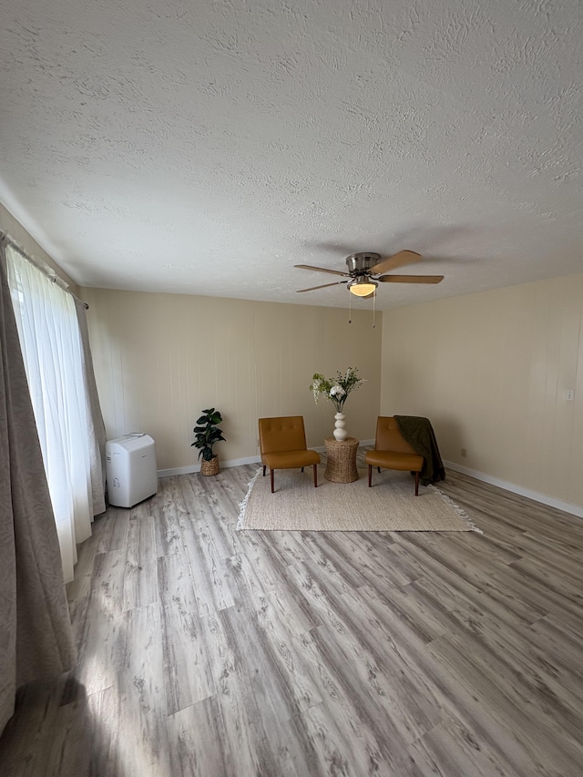 unfurnished room featuring ceiling fan, a textured ceiling, and light hardwood / wood-style flooring