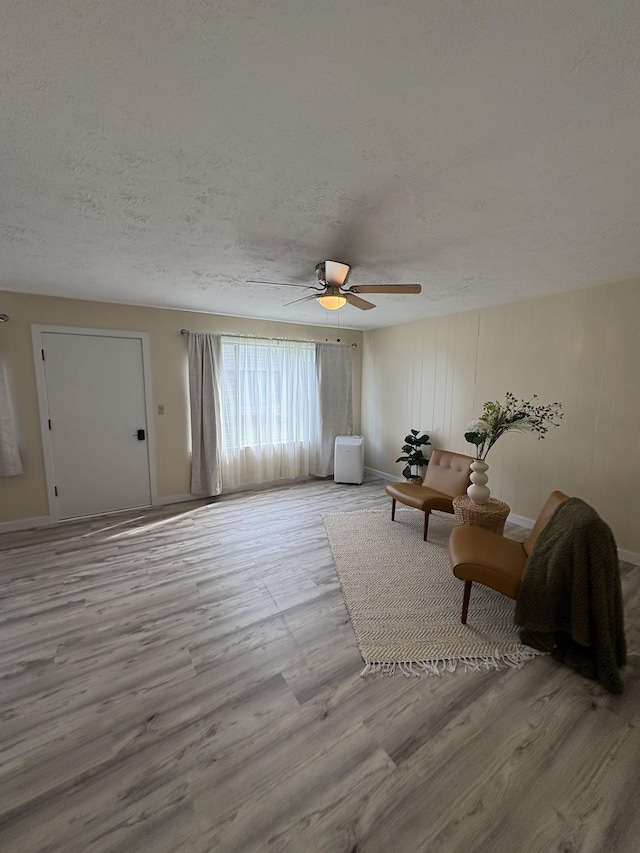 unfurnished living room with ceiling fan, a textured ceiling, and light hardwood / wood-style flooring