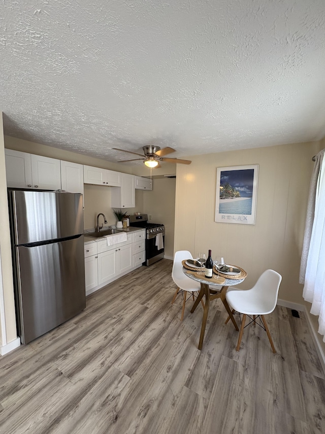 dining area with light hardwood / wood-style floors, sink, a textured ceiling, and ceiling fan