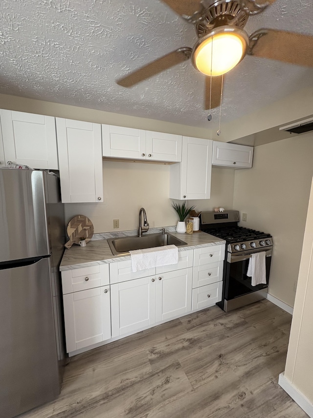 kitchen with white cabinetry, ceiling fan, stainless steel appliances, light wood-type flooring, and sink