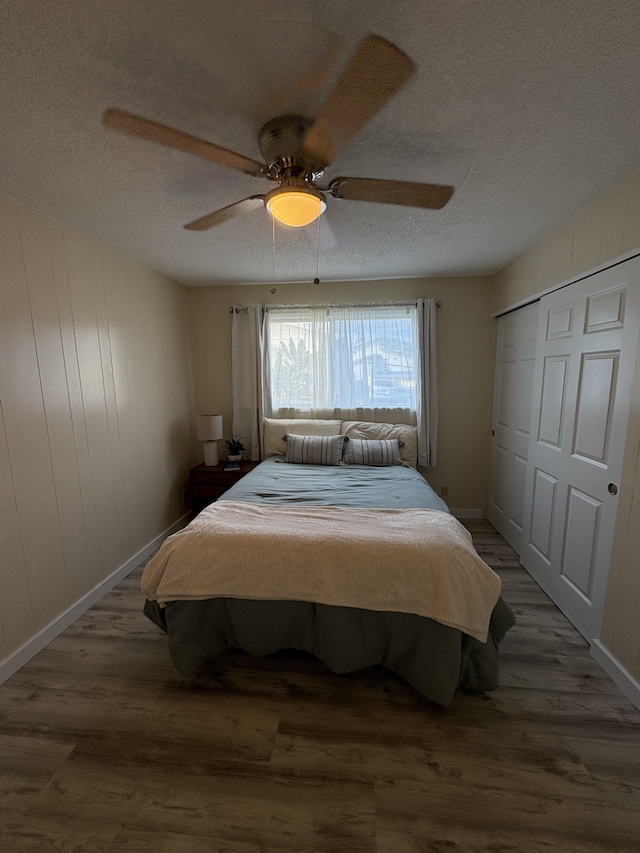 bedroom with ceiling fan, a closet, dark hardwood / wood-style floors, and a textured ceiling