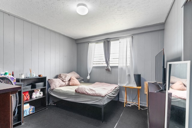 bedroom with a textured ceiling and wood walls