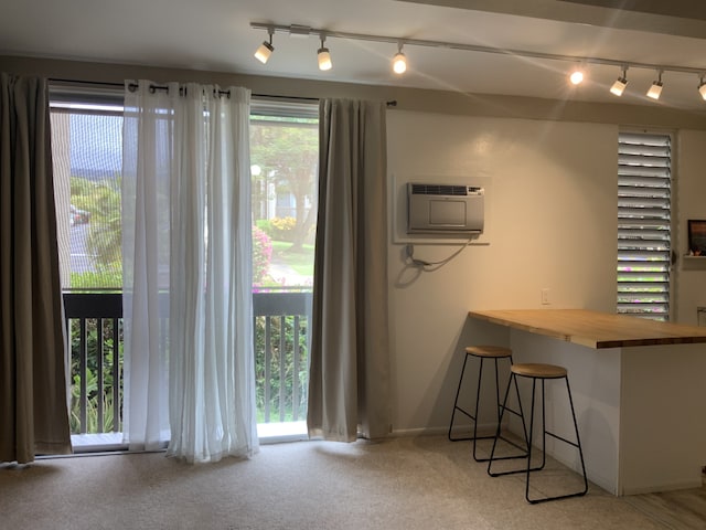 kitchen with baseboards, a kitchen breakfast bar, a wall mounted air conditioner, carpet, and wooden counters