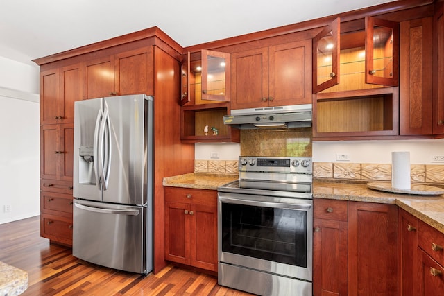 kitchen featuring tasteful backsplash, light stone countertops, stainless steel appliances, and light hardwood / wood-style floors