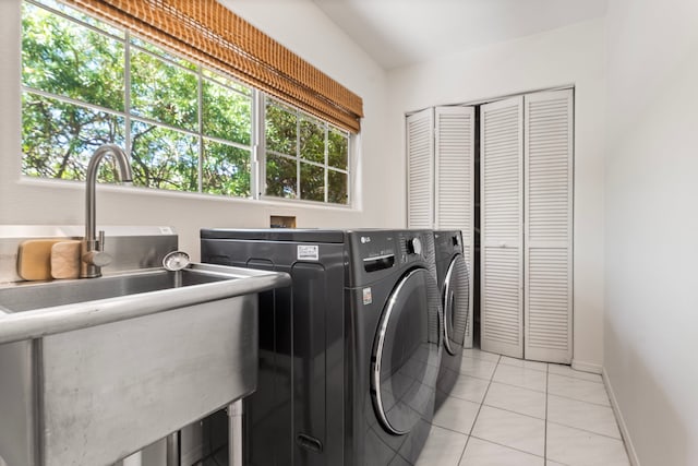 clothes washing area with sink, washer and dryer, and light tile patterned floors