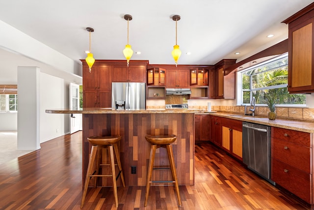 kitchen featuring pendant lighting, stainless steel appliances, a center island, and decorative backsplash