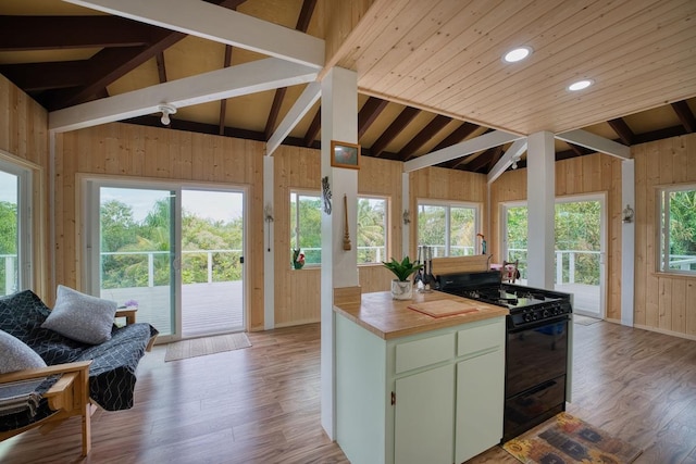 kitchen with lofted ceiling with beams, butcher block counters, black gas range, and light hardwood / wood-style floors