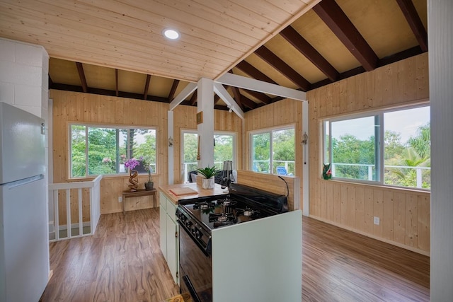 kitchen featuring plenty of natural light, light wood-type flooring, lofted ceiling, white refrigerator, and black range with gas stovetop