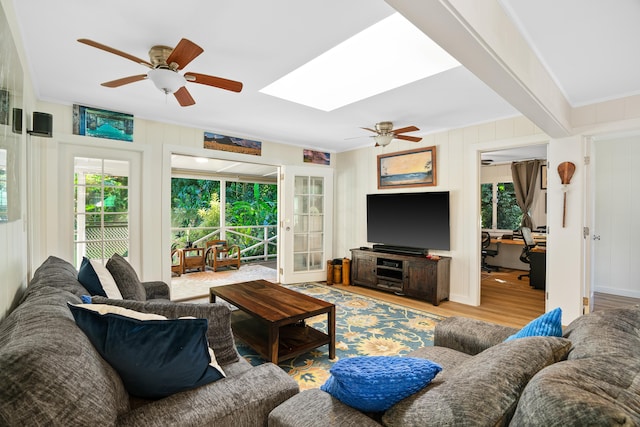 living room with ornamental molding, ceiling fan, light hardwood / wood-style floors, and a skylight