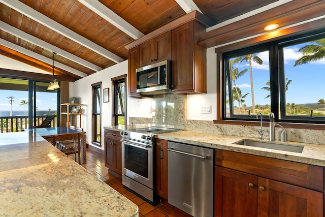 kitchen with decorative light fixtures, stainless steel appliances, sink, lofted ceiling with beams, and light stone counters