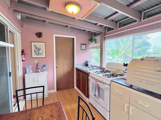 kitchen with sink, light hardwood / wood-style flooring, beamed ceiling, and white gas stove