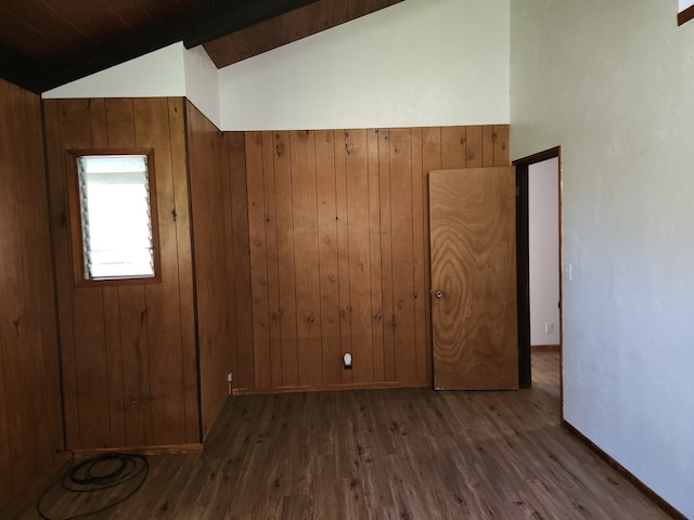 additional living space with wooden walls, baseboards, vaulted ceiling, and wood finished floors