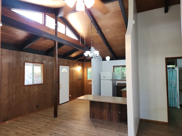 kitchen with wooden ceiling, wood walls, wood finished floors, freestanding refrigerator, and beamed ceiling