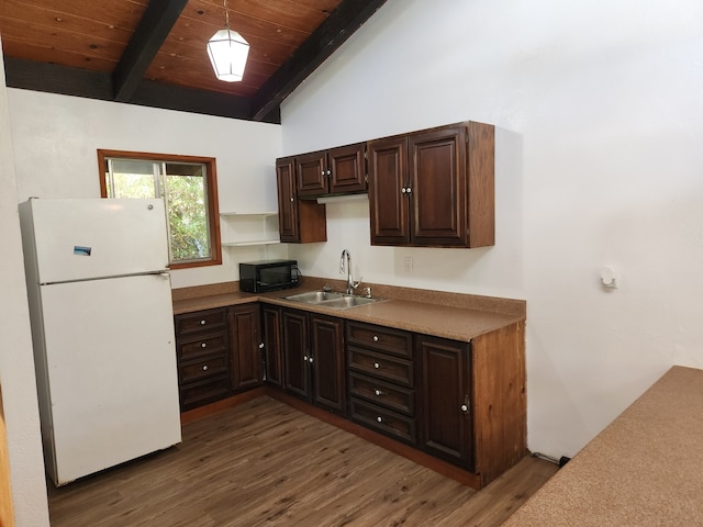 kitchen with vaulted ceiling with beams, freestanding refrigerator, a sink, dark brown cabinets, and black microwave