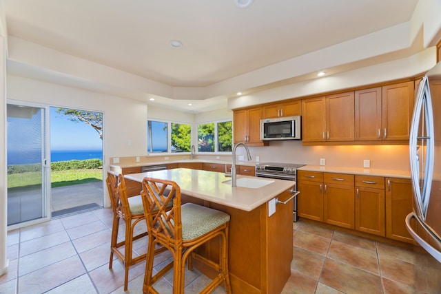 kitchen with appliances with stainless steel finishes, a breakfast bar, sink, and a center island with sink