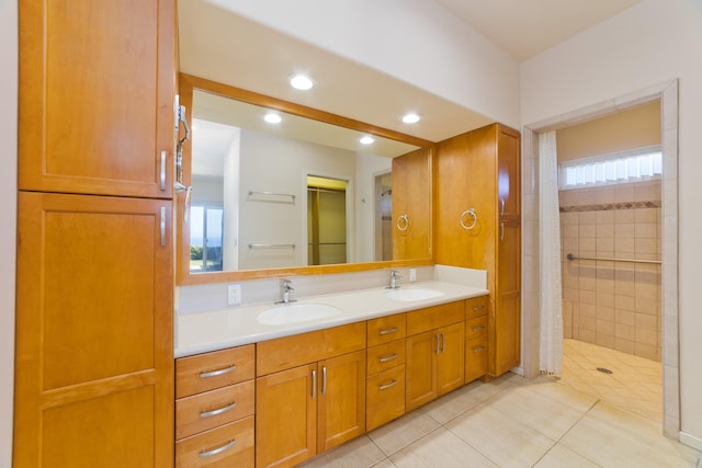 bathroom with a tile shower, vanity, and tile patterned floors