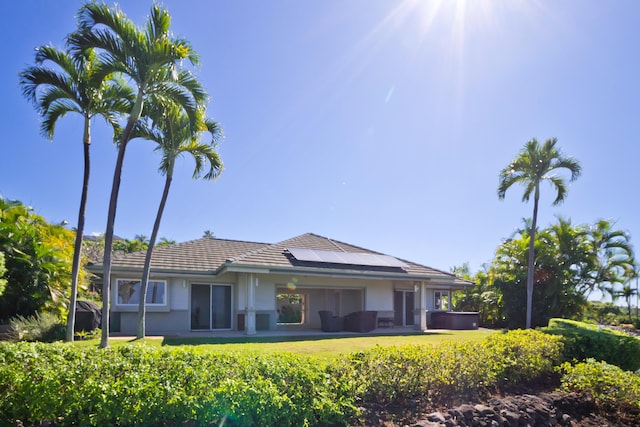 rear view of house with a hot tub and solar panels