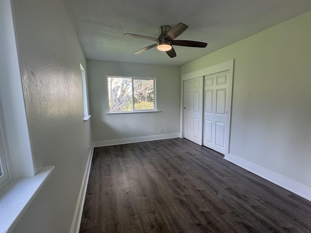 unfurnished bedroom with ceiling fan, dark wood-type flooring, a textured ceiling, and a closet