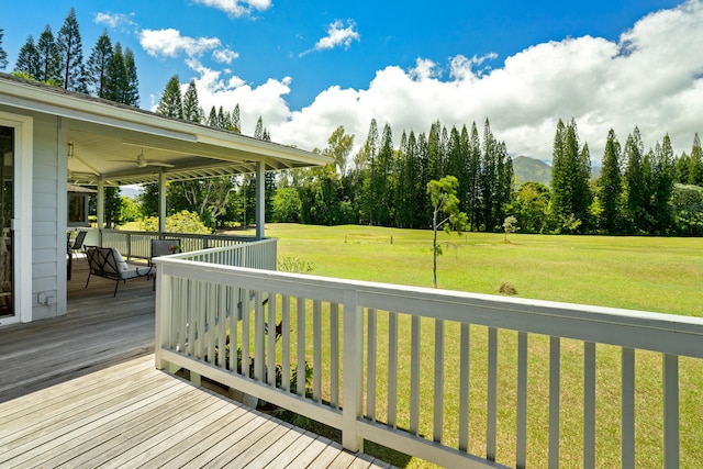 deck with a ceiling fan and a lawn