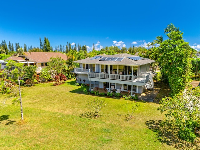 rear view of house featuring a deck, solar panels, a yard, and stairway