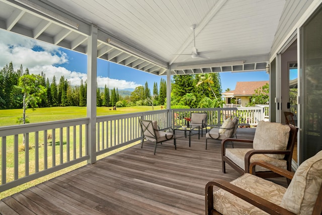 wooden terrace featuring a ceiling fan and a yard