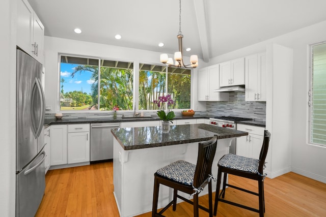 kitchen with under cabinet range hood, white cabinetry, a kitchen island, and appliances with stainless steel finishes